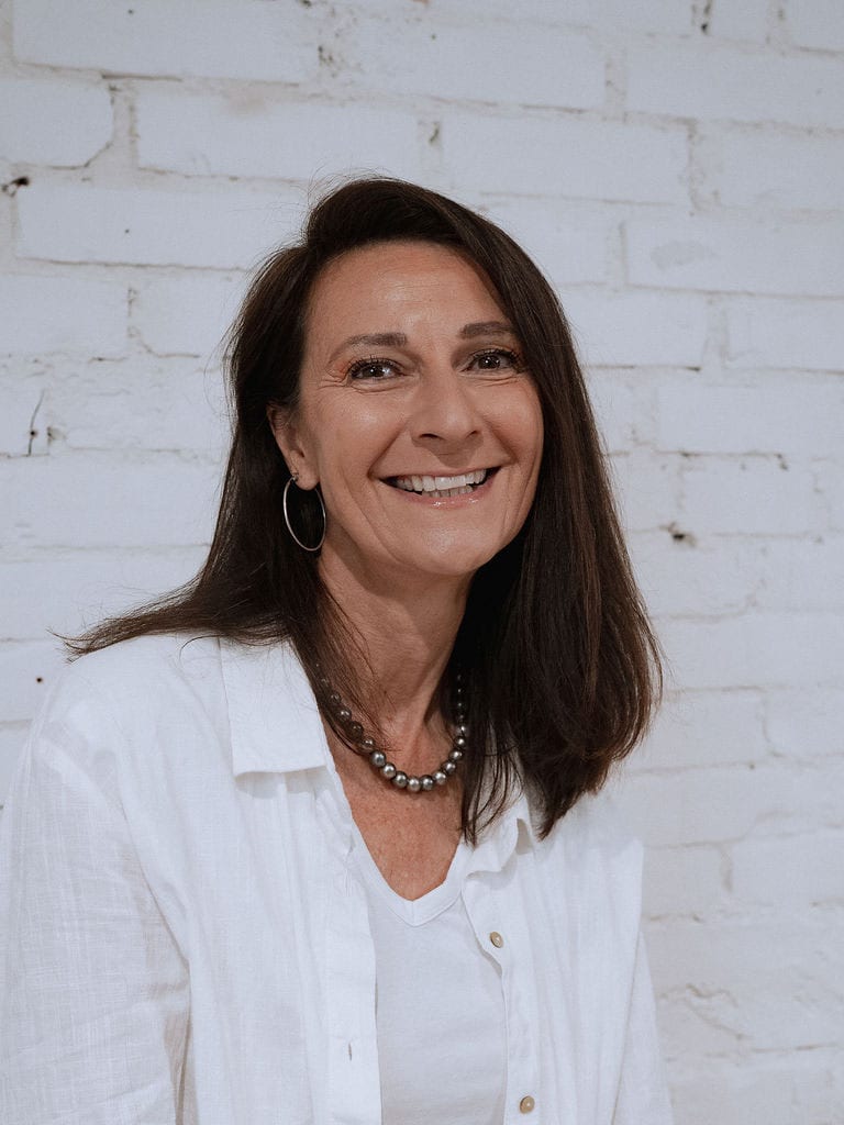 Daniela Willi-Otz vor einer weiss gestrichenen Backsteinwand